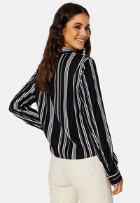 Zwart-wit gestreepte blouse met lange mouwen en een kraag, met een losse pasvorm en knoopmanchetten. Glad materiaal met een strakke uitstraling.