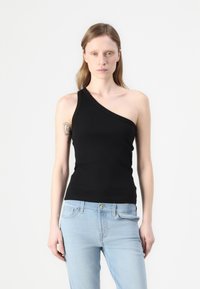 Black, one-shoulder tank top made of ribbed fabric. Paired with light blue jeans. Minimalist design with a fitted silhouette and subtle texture.