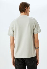 Lys grå kortærmet t-shirt med rund halsudskæring, blød tekstur og en afslappet pasform, parret med sorte jeans. Ingen synlige mønstre eller logoer.