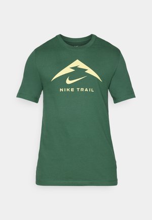 Grünes kurzärmeliges T-Shirt aus Baumwolle. Mit einem großen gelben Berglogo und dem Text "NIKE TRAIL" auf der Vorderseite. Einfacher Rundhalsausschnitt.