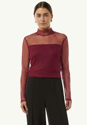 Burgunderrot Bluse mit langen Ärmeln aus transparenter Stoff, hohem Kragen und schimmernden Details. Enganliegendes Oberteil und fließendes Material, kombiniert mit schwarzen Hosen.