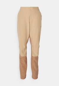 Beige byxor med en kontrasterande ljusbrun nederdel, med en slät yta, sidofickor och en framknäppning med knappar.