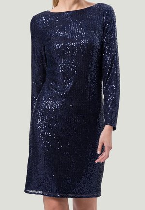 Navyblaues, langärmeliges Kleid, bedeckt mit schimmernden Pailletten, getragen von einer Frau, gezeigt vom Hals bis zu den Knien vor einem einfachen Hintergrund.