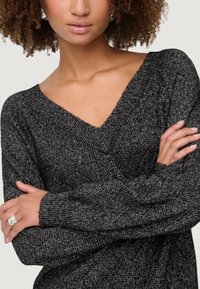 Maglione lavorato a maglia nero e argento con scollatura a V, caratterizzato da un motivo testurizzato, maniche lunghe e polsini a coste.