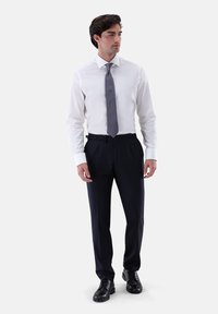 Weißes Hemd, graue gemusterte Krawatte, marineblaue Hose, schwarze Schnürschuhe. Glatter Stoff, maßgeschneiderte Passform, geknöpfte Manschetten und sichtbare Gürtelschlaufen.