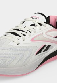 Άσπρο και ροζ παπούτσι τρεξίματος Reebok με άσπρα κορδόνια και μαύρες λεπτομέρειες, που δείχνει λεπτομερή πλευρική και πάνω όψη.