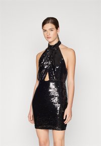 Crna haljina s šljokicama i halter izrezom, s ključnom rupom, prilagođenim siluetom i blistavom teksturom, koja stvara elegantan, prilagodljiv dizajn.