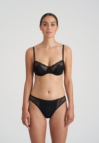 Svart spetsbh och matchande trosor. Bh:n har byglar, justerbara band och blommig spetsdetalj. Trosorna har spetsaccenter och vågiga kanter.