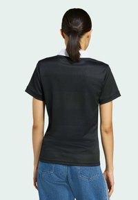 Svart kortärmad polo tröja med vit krage, tillverkad av texturerad mesh tyg, med avslappnad passform och synliga sömdetaljer.