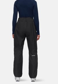 Zwarte skibroek met ritszakken aan de zijkant, een hoge taille en mesh-panelen bij de onderbenen. Voorzien van een versterkt ontwerp van Mammut.