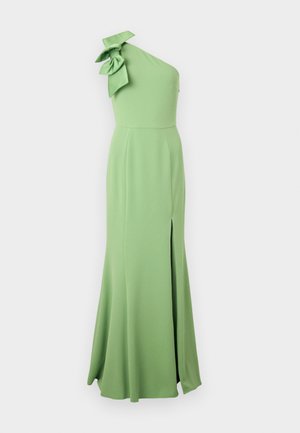 Jednoduché dlouhé zelené šaty na jedno rameno vyrobené z hladkého materiálu, které mají velkou mašli na rameni a boční rozparek pro větší pohyb.