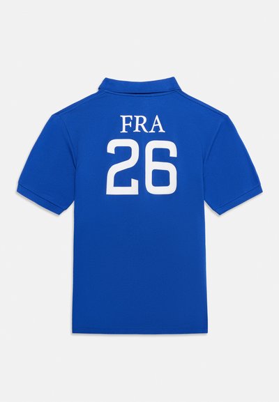 Μπλε κοντομάνικη πόλο μπλούζα με λευκό κείμενο "FRA" και αριθμό "26" στην πλάτη, απλό φόντο.