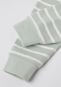 Vihreä raidoitettu kangas, jossa näkyy kaksi hihaa pehmeällä tekstuurilla. Hihansuut ovat tasaisen vihreät, joissa on valkoisia raitoja kankaan yli.