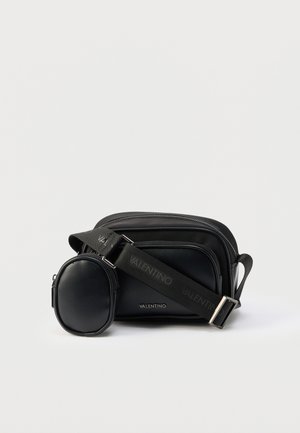 Bolso bandolera negro de Valentino con pequeño bolso ovalado desmontable y correa ajustable con la marca, sobre fondo blanco.