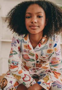 Ensemble de pyjama pour enfants, tissu en coton, fond blanc, illustrations colorées de nourriture et d'objets, conception à boutons, et poche poitrine.