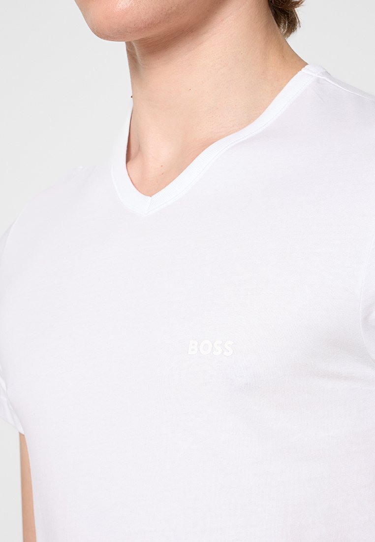 Biała bawełniana koszulka z dekoltem w serek, z delikatnym wytłoczonym logo "BOSS" na piersi. Gładka tekstura, dopasowany krój.