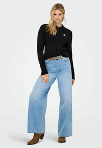 Juodas megztinis su apykakle, pintas, derinamas su šviesiai mėlynomis plačiomis kelnėmis. Rudos kulkšninių botai. Paprasti akcentai ir laisvas fasonas.