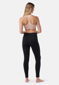 Lichtroze sportbeha met kruislings gekruiste bandjes, gecombineerd met zwarte hoge taille legging, met een soepele textuur en zonder zichtbare patronen.