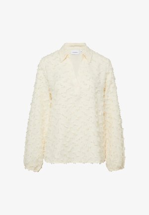 Kremowa bluzka z długim rękawem z teksturowanymi kropkowymi detalami, dekoltem w kształcie litery V, kołnierzykiem i elastycznymi mankietami.