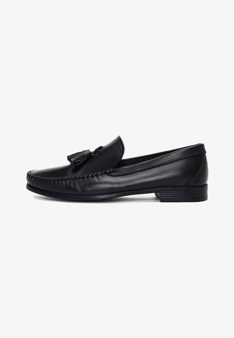 Mocassin homme en cuir noir avec détail pompon, bout mocassin cousu et petit talon empilé, vu de côté sur fond blanc.