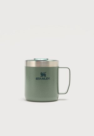 Taza de viaje de metal texturizado verde con asa y borde de acero inoxidable, con el logo de Stanley en el frente y una tapa transparente.
