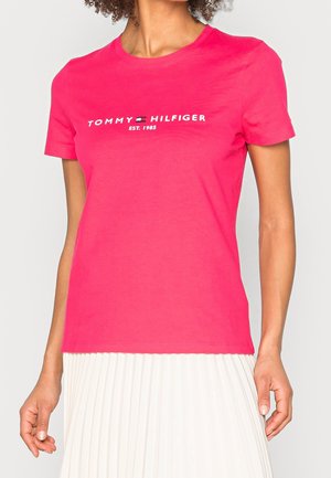 Krátký rukáv, jasně růžové bavlněné tričko s bílým logem "TOMMY HILFIGER" a textem "EST. 1985", kulatý výstřih a pohodlný střih.