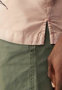 Jasnoróżowy materiał o gładkiej strukturze, z bocznym rozcięciem. Zestawiony z ciemnozielonym materiałem z prostym szwem po boku.