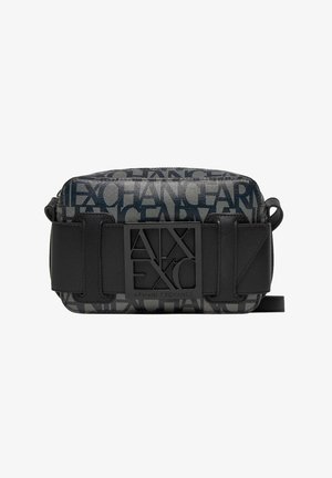 Černá a šedá crossbody taška s plátěným vnějším povrchem, která má výrazný design loga a odvážný černý popruh s přezkou.