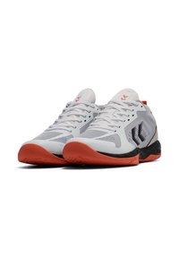 Witte sportieve schoenen met gaaspanelen, zwarte accenten en oranje zolen. Heeft een laag ontwerp en traditionele veters.