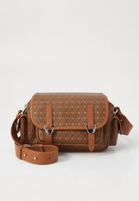 Brūna somiņa ar rakstu, izgatavota no teksturēta materiāla. Aprīkota ar sudraba krāsas metāla detaļām, divām regulējamām siksnām un atloku ar sprādzēm.