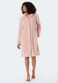 Rosa fleece-kappa med knappfäste framtill, krage och två sidofickor. Har långa ärmar och en mjuk, texturerad yta.