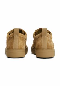 Tan-Filzschuhe mit einem niedrigen Profil, strukturiertem Obermaterial und einer Zuglasche auf der Rückseite. Gummisohlen sorgen für Grip und Stabilität.