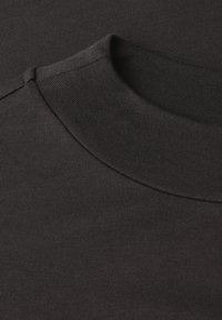 Zwarte katoenen T-shirt met een ronde hals, heeft een gladde textuur en een ribbelkraag. Geen patronen of hardware zichtbaar.