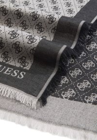 Grey and black patterned scarf featuring a fringe edge, with a diamond design and logo accents, made from a soft, textured material.
