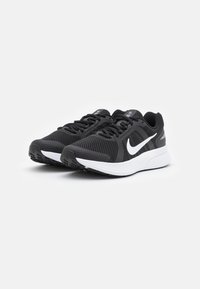 Chaussures de sport noires avec une tige en mesh, logo swoosh blanc, semelle intermédiaire amortissante et semelle extérieure en caoutchouc texturé pour une meilleure traction.