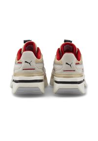 Beige und rote Sportschuhe mit einem Obermaterial aus Mesh und Wildlederdetails. Dicke weiße Laufsohle mit schwarzem Streifen, mit Puma-Branding an der Ferse.