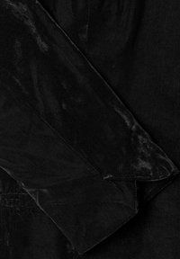 Mustast sametist kangas, mille servad on kokku voltitud ja õmbluse detailid nähtavad, makrovaade.