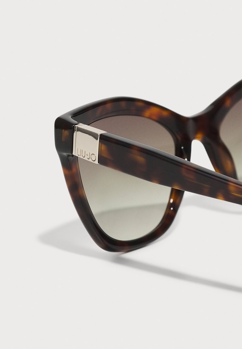 Sonnenbrille aus Schildpatt mit geometrischer Form, Verlaufsgläsern und einem silbernen Akzent am Bügel mit "LIU JO" Branding.