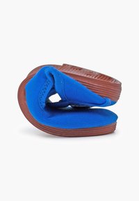 Blauwe stoffen schoen met een flexibel ontwerp, voorzien van een bruine rubberen zool en een gestructureerd oppervlak. De schoen wordt gepresenteerd in een gebogen positie.