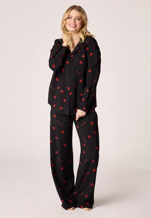 Black pajama set featuring a button-up top and matching wide-leg pants, adorned with red heart patterns and scripted accents throughout.
