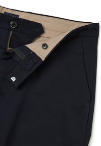 Donkerblauwe broek met een beige voering, ritssluiting en twee voorzakken. Inclusief knoopaccenten voor een veilige sluiting.
