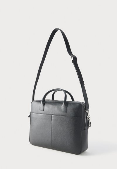 Μαύρη δερμάτινη τσάντα εργασίας με διπλές λαβές και ρυθμιζόμενο ιμάντα ώμου, απεικονίζεται σε απλό ανοιχτό φόντο.