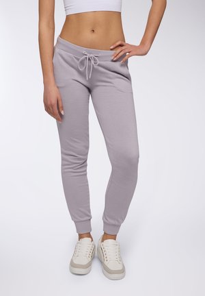 Pantaloni della tuta viola chiaro realizzati in morbido tessuto, con vita elasticizzata e cordoncino, e polsini a coste, abbinati a sneaker bianche.