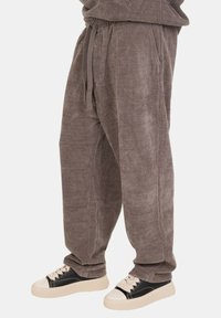 Pantaloni in corduroy grigi con vita elastica e coulisse, caratterizzati da una vestibilità comoda e tasche laterali, abbinati a sneakers nere e crema.