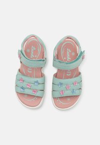 Sandali azzurri chiari con tre cinturini regolabili, decorati con applicazioni a forma di stelle rosa e blu, e una soletta rosa texturizzata.