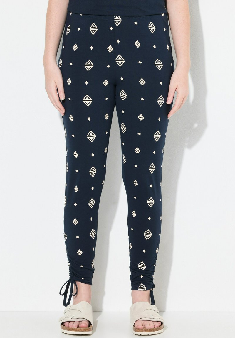 Námořnické legíny vyrobené z pružné tkaniny, s geometrickým krémovým vzorem, upnutým střihem a staženými kotníky se šnůrkami.