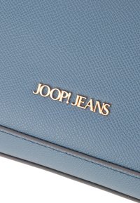 Borsa in ecopelle testurizzata di colore azzurro chiaro, caratterizzata da un logo "JOOP! JEANS" in tono oro, cuciture finemente dettagliate e un design elegante e minimalista.