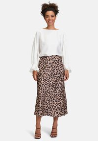 Weiße Bluse mit langen puffärmel, kombiniert mit einem Midikleid im Leopardenmuster. Glatte Stoffe, elegante Silhouette und Riemchenhe als Absatzschuhe.