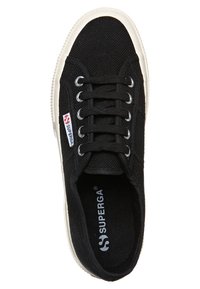 Sneaker nera in tela con superficie testurizzata, suola in gomma bianca, sei occhielli e etichetta logo rossa/bianca laterale. Chiusura con lacci piatti.