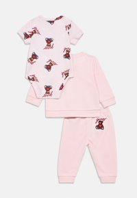 Το σετ περιλαμβάνει ένα ροζ κοντομάνικο φορμάκι με στάμπα αρκούδας και λογότυπο, καθώς και ένα αντίστοιχο ροζ φούτερ και παντελόνι με παρόμοιο λογότυπο.